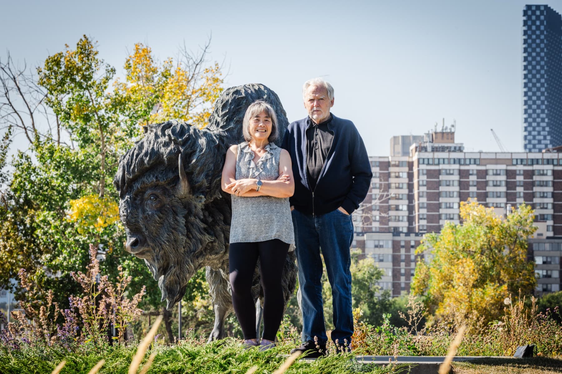Nick and Madeline of Legacy Energy beside a bison sculpture with the Calgary skyline behind them